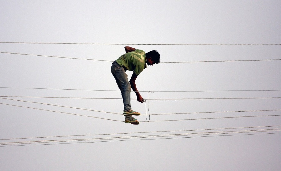 A power company worker stands on electricity transmission lines while making adjustments in the city of Sangam in Allahabad, India, ahead of the Maha Kumbh Mela festival. AFP